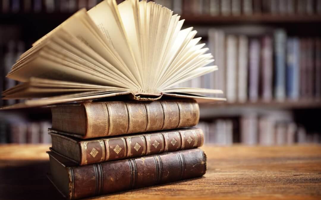 Open book on top of a stack of closed books.